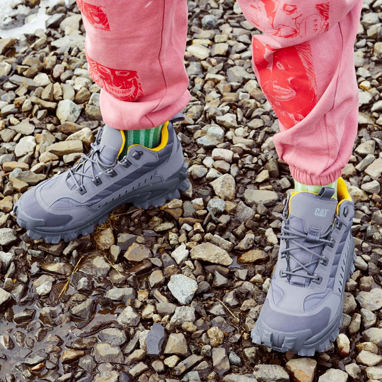 Les pieds d'une personne dans des chaussures Intruder Mid grises sur des rochers.