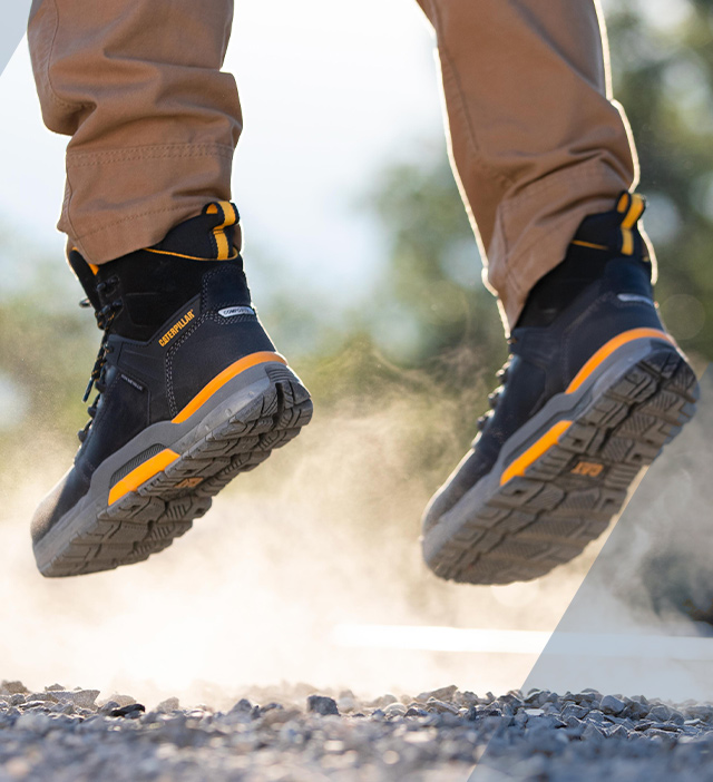 A person walking at a work site, wearing CAT Edge boots.