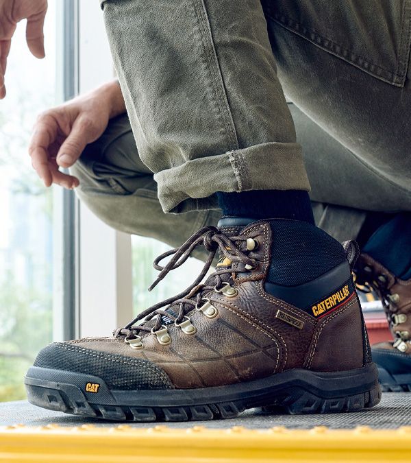 Vue rapprochée du pied d'une personne portant la botte de travail Threshold de CAT en marron.