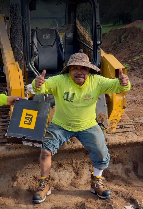 Worker giving two thumbs up while holding a Cat Footwear shoe box.