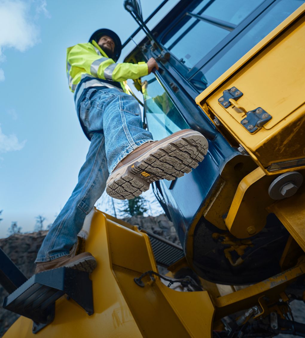 Boots standing on the footplate of a bulldozer.