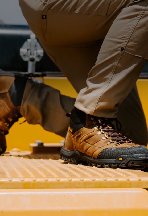 Kneeling on heaving equipment wearing brown boots.