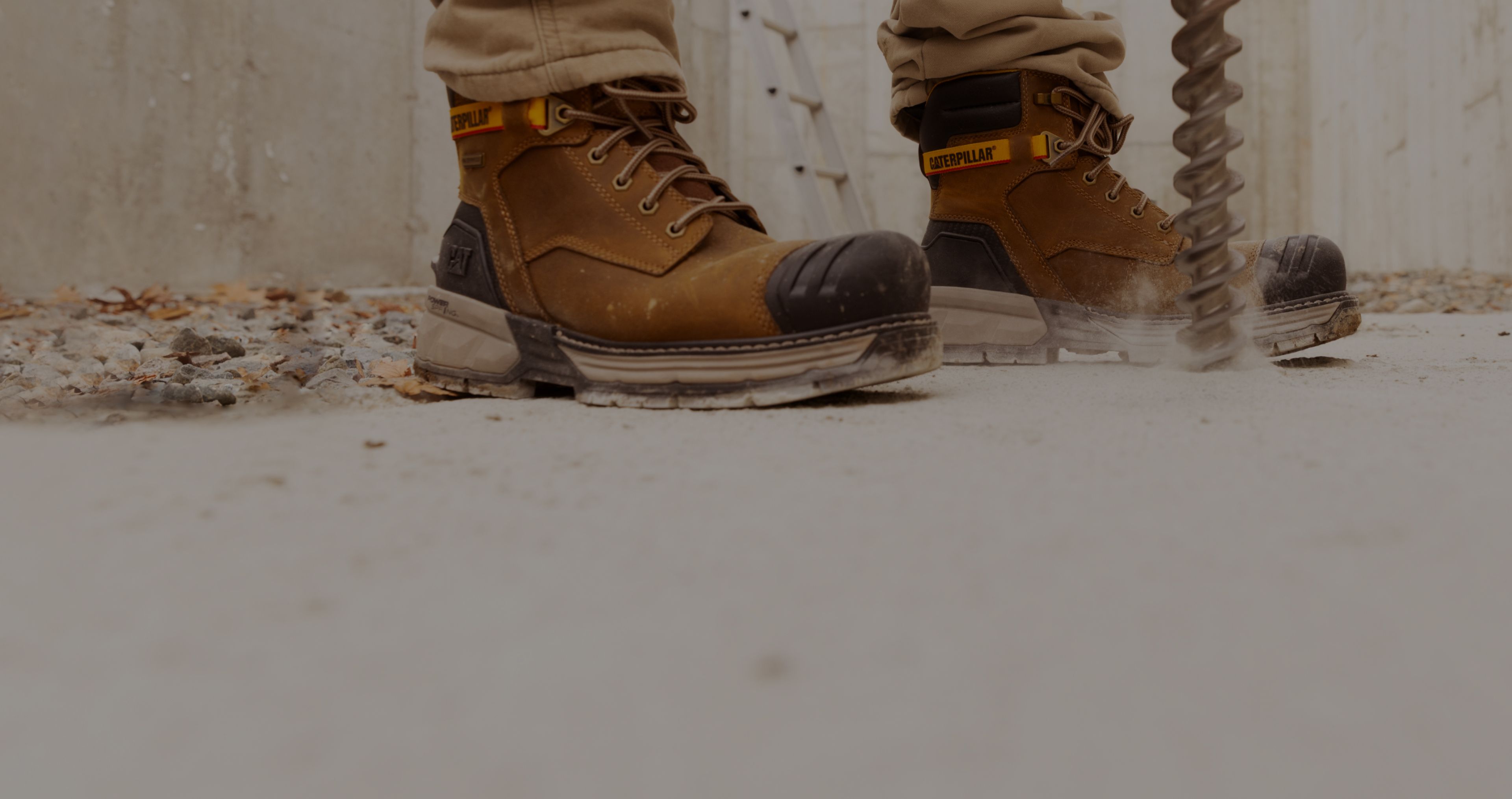 Boots standing beside a large drill boring into a concrete slab.
