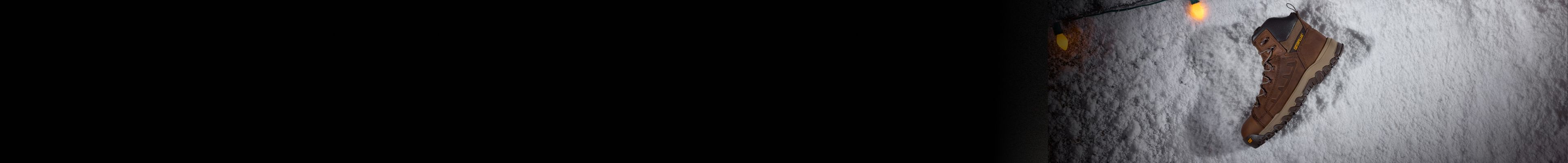 Boots in the snow, surrounded by holiday lights.