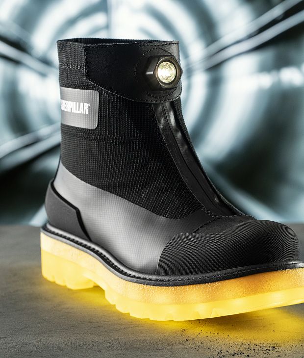 Black boot with yellow sole in front of a tunnel entrance.