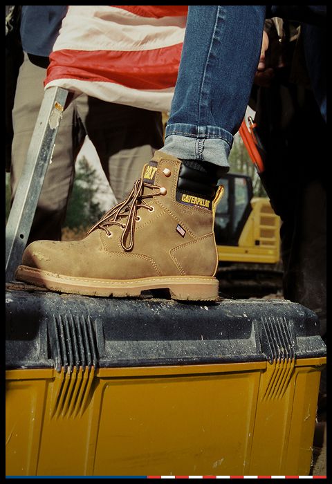 Brown & black boots standing on a drinks cooler.