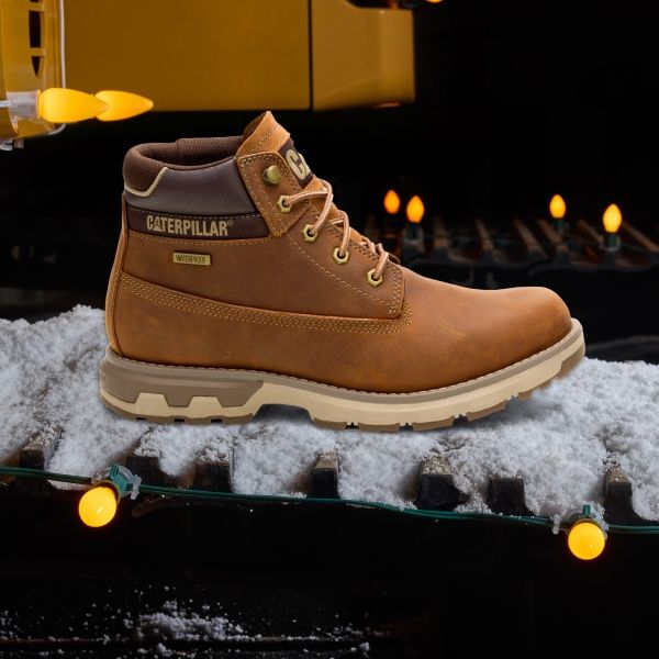 Brown waterproof Pursue boots on a snowy caterpillar track, surrounded by string lights.