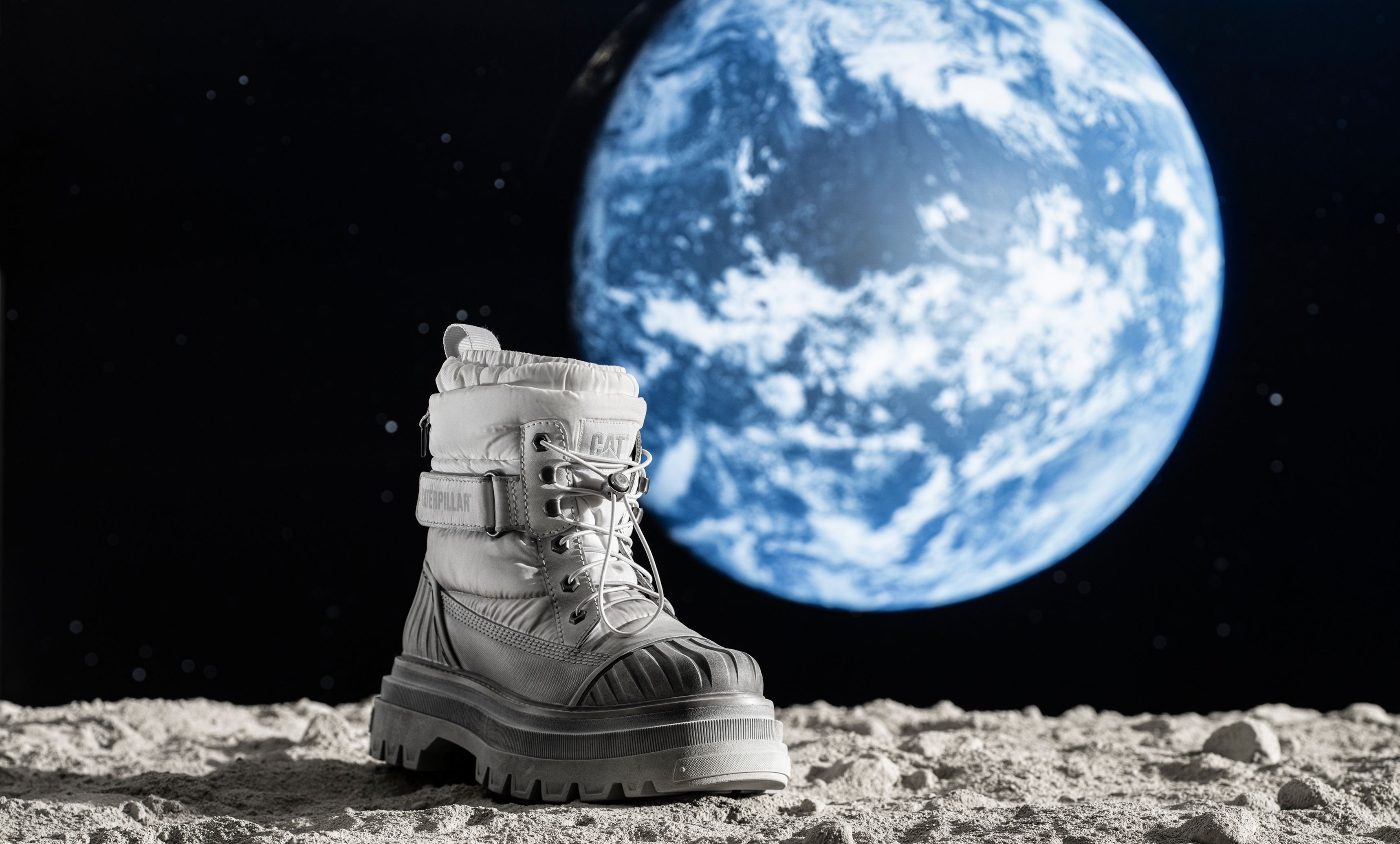 Apollo 11 boot on the lunar surface with planet Earth in the background.