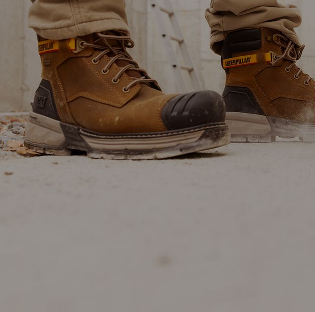Boots standing beside a large drill boring into a concrete slab.