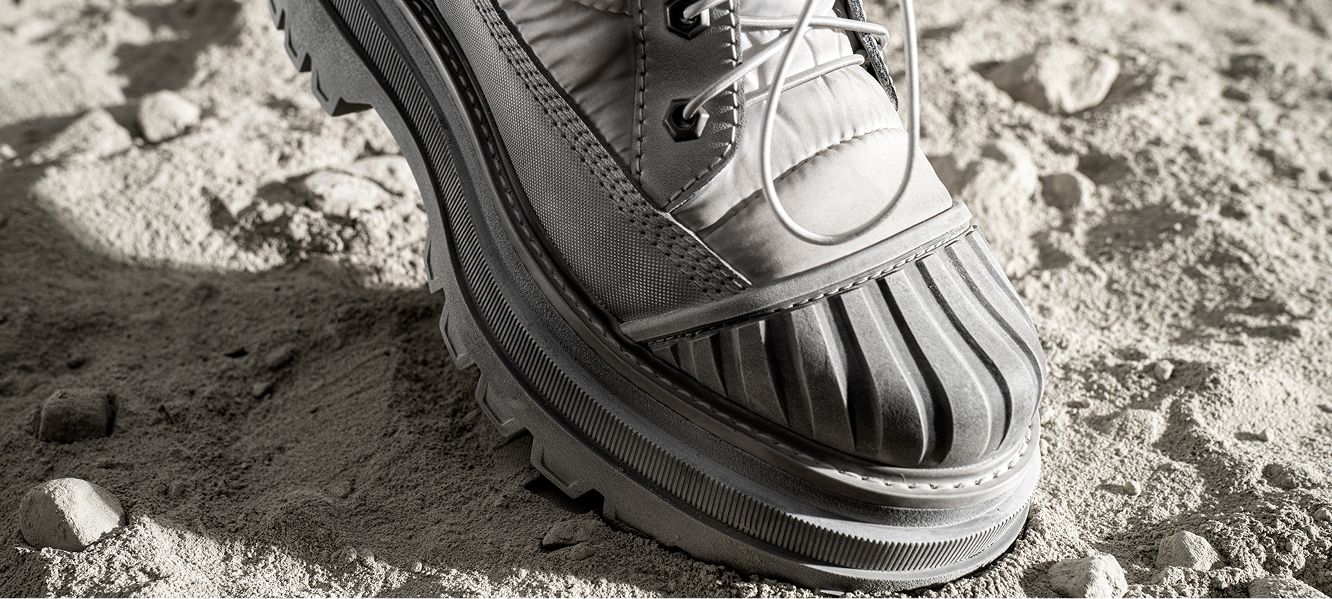 Light grey boot on a dusty lunar surface.