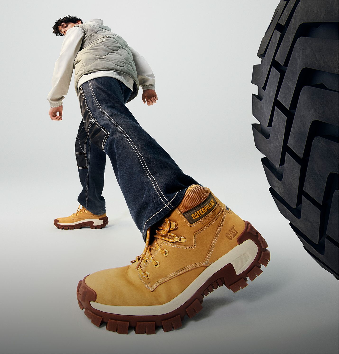 Boots standing next to a large tire.