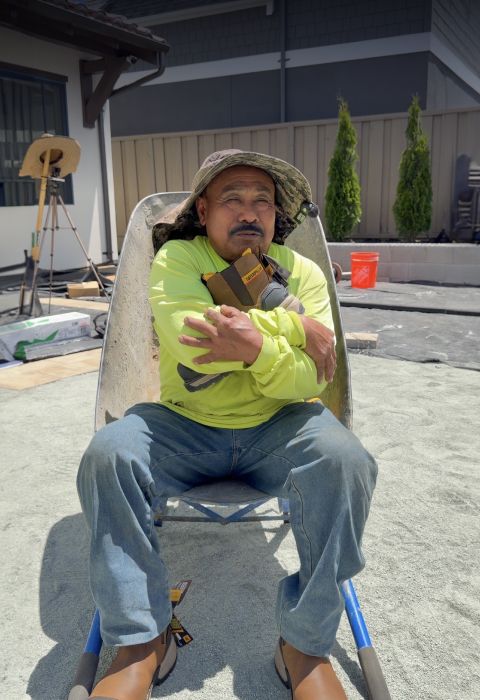 Worker resting in a wheelbarrow holding a Cat Footwear shoe box.