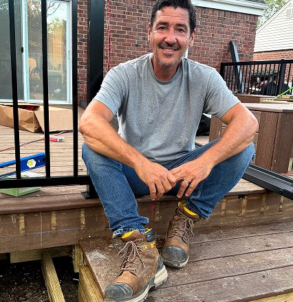 Jonathan wears brown boots while sitting on deck steps.